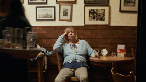 The Ballad From Wednesday to Thursday film image; woman looking defeated seated at a table