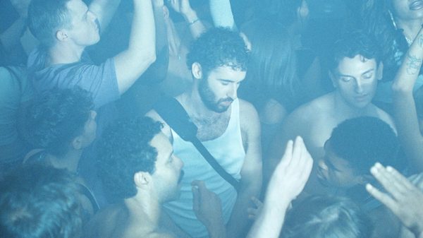 Club Kid film image; people dancing in a crowd in hazy lighting