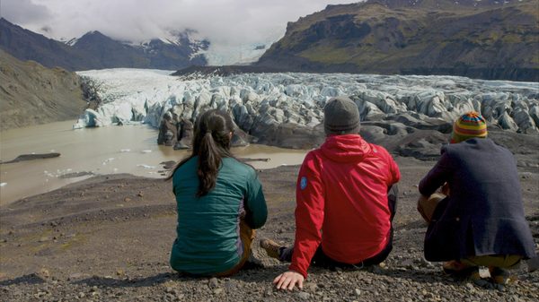 Chasing Time film image; three people sitting near a glacier