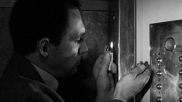 Elevator to the Gallows film image; man holding a lighter up to an elevator panel