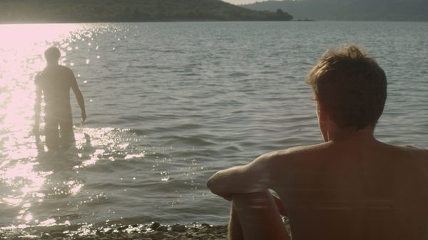Stranger by the Lake film image; person on beach staring at person walking out of water