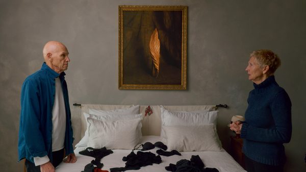 Two Strangers Trying Not to Kill Each Other film image; two people standing at opposite sides of a bed