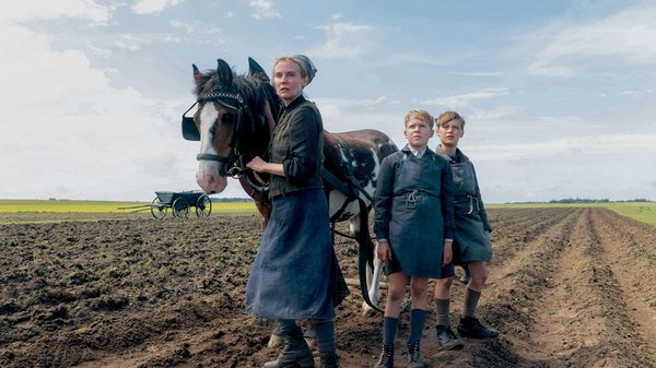 Amrum film image; three people leading a horse through a barren field