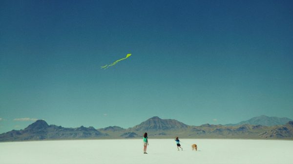 Omaha film image; two far-away figures flying a kite over a barren landscape