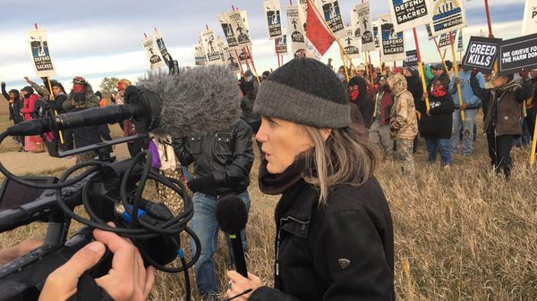 Steal This Story, Please! film image; woman in a crowd with news equipment