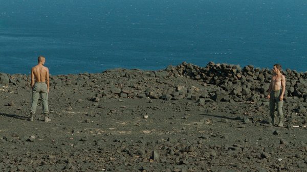 Beau Travail film image; two people on a rocky beach