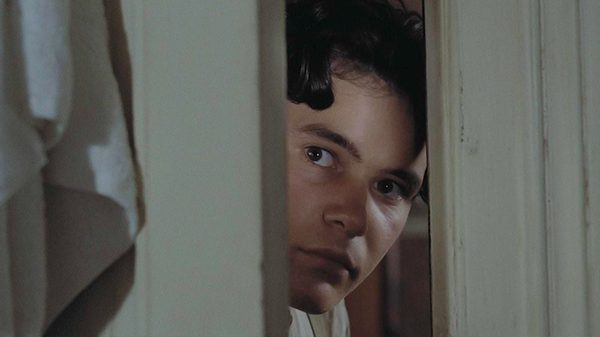 Lacombe, Lucien film image; person looking through a partially opened door