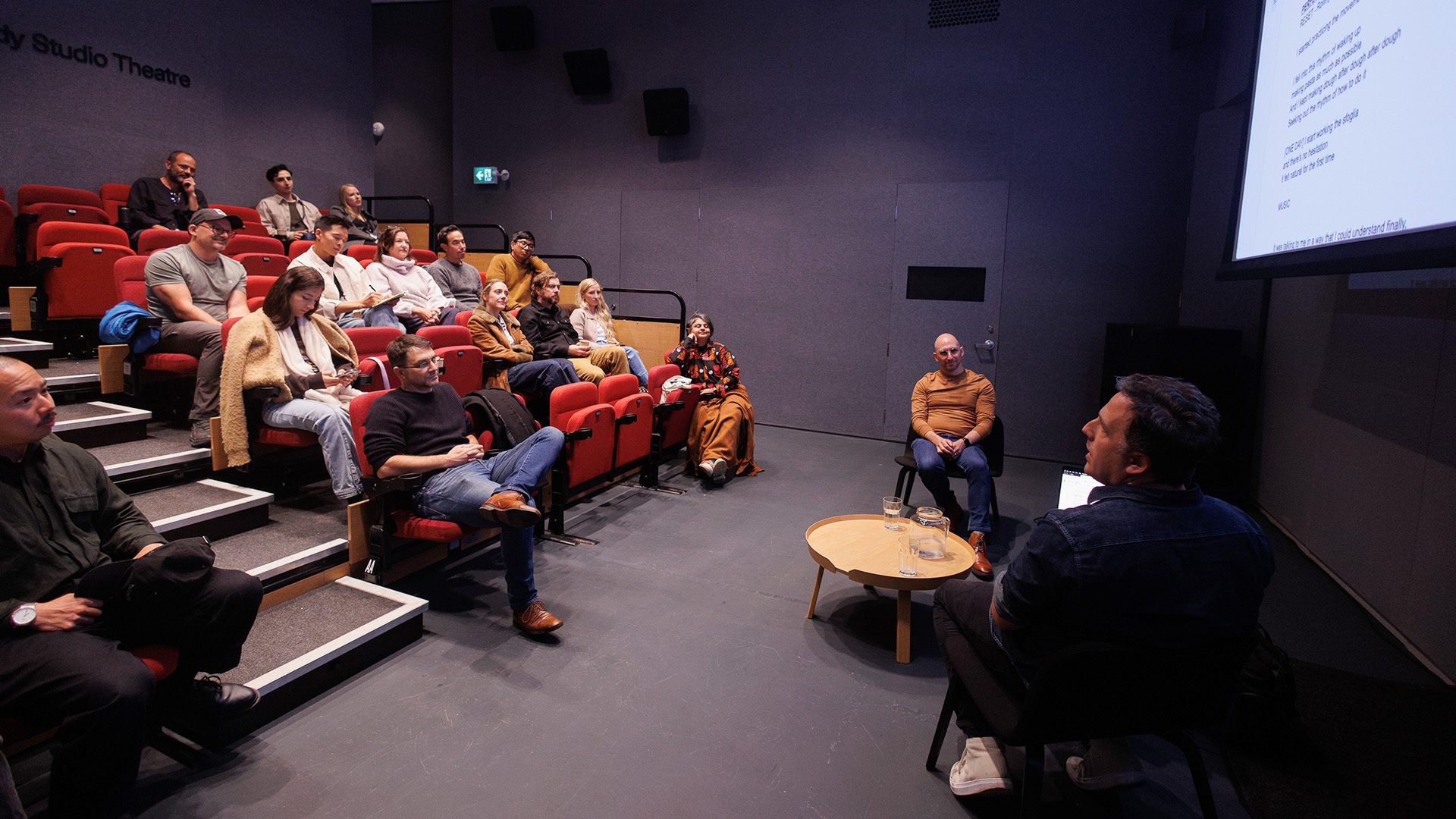 people in an audience watching a panel discussion