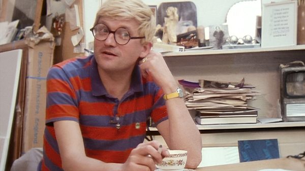 Hockney film image; man sitting at a table