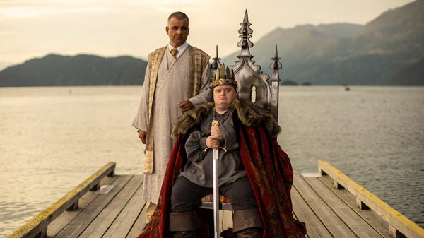 King Arthur's Night film image; man on a throne with a man standing behind him