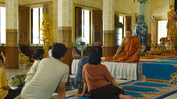9 Temples to Heaven film image; people seated on the ground listening to a monk