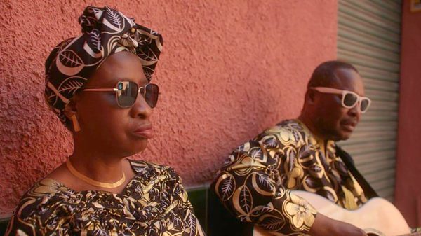 Amadou & Mariam film image; two people sitting against a red wall