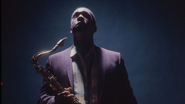 Chasing Trane film image; man holding a saxophone and looking up