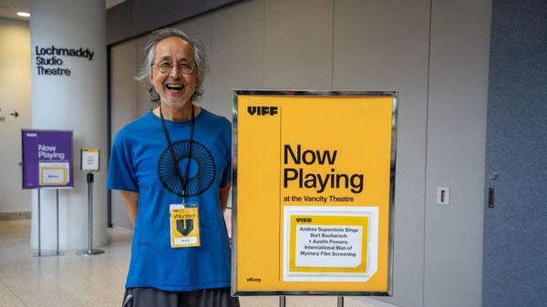 person smiling next to a sign