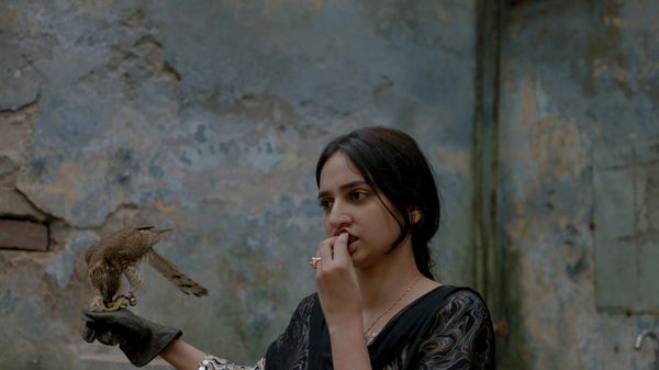 Lali film image; woman in a corner pressing her fingers to her lips