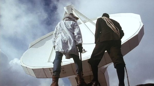 two people staring up at a giant satellite dish