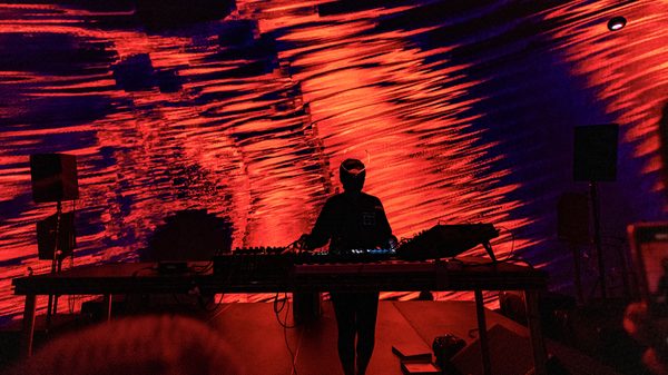 person playing a keyboard on stage under red lighting
