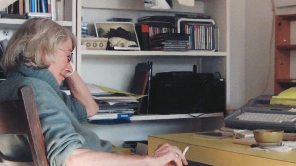 Mary Oliver film image; woman sitting at a desk lost in thought