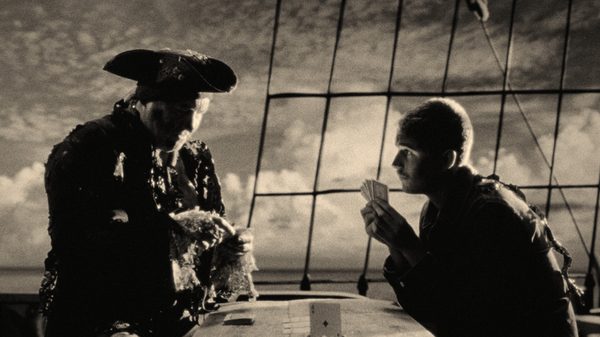 The Peril at Pincer Point film image; two people playing cards on a ship deck