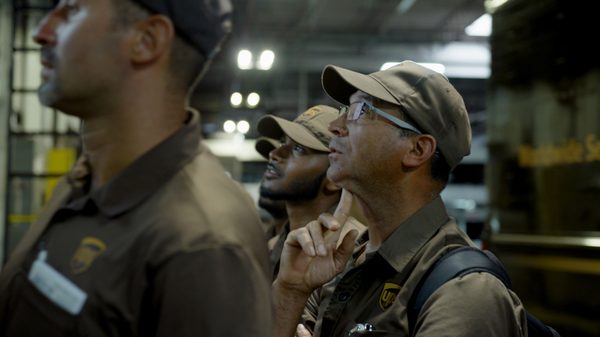 Who Moves America film image; UPS workers looking at a board