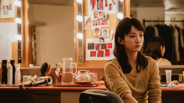 Afterpiece film image; woman in a dressing room facing away from the mirror