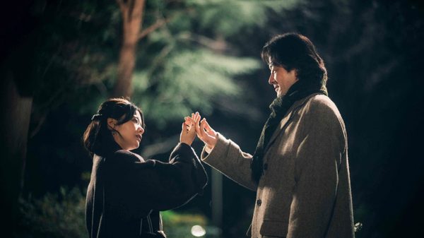 All the Lovers in the Night film image; man and woman touching the backs of their hands together