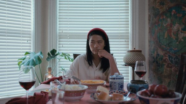 Already Happened film image; woman sitting at a table with bowls of food