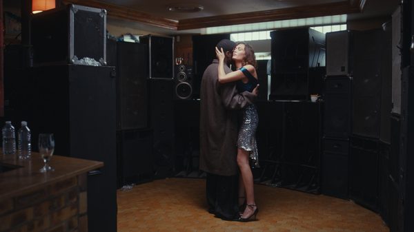 The Blessing film image; man and woman in an embrace in a room full of speakers