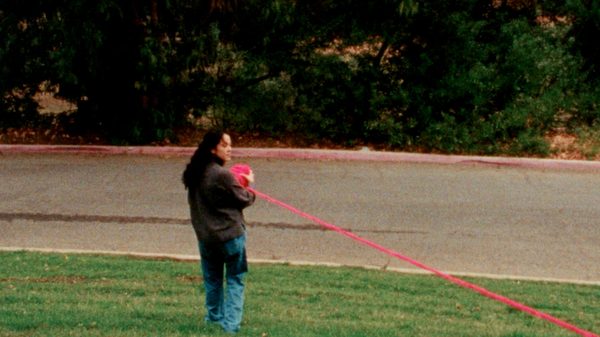Cartografía film image; person holding a bundle of red tape