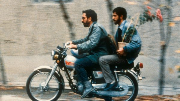 Close-Up film image; two people riding a motorcycle down the street