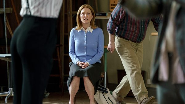 The Debut film image; woman sitting in a char as people walk past her
