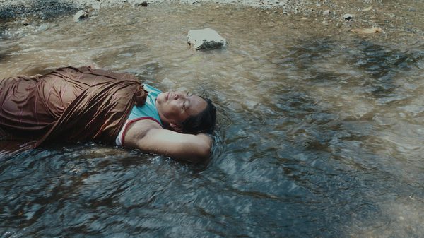 A Distant Call film image; person lying on their back in shallow water