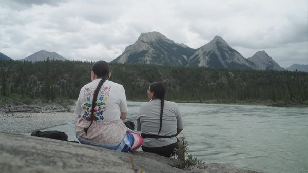 Endless Sunlight film image; two people sitting at the edge of a lake