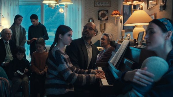 Fjord film image; people gathered around a piano