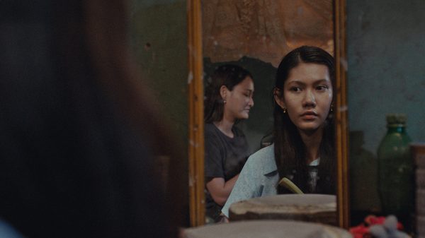 Fruit Gathering film image; woman looking at herself in a mirror