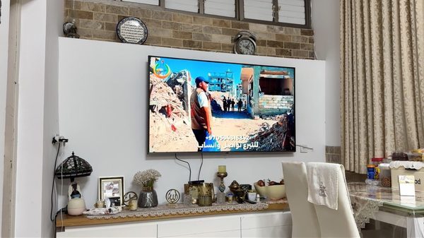 Going Home film image; a television mounted on a wall above a cluttered shelf