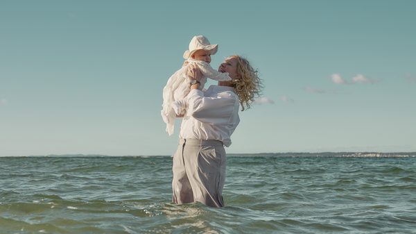 The Guest film image; woman holding a baby while standing in the ocean