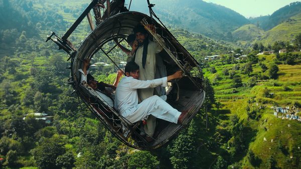 Hanging by a Wire film image; men hanging in exposed container in the air