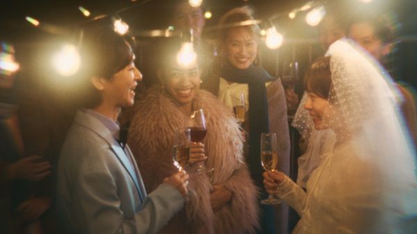 Husband's Legs film image; people celebrating a wedding outside under fairy lights