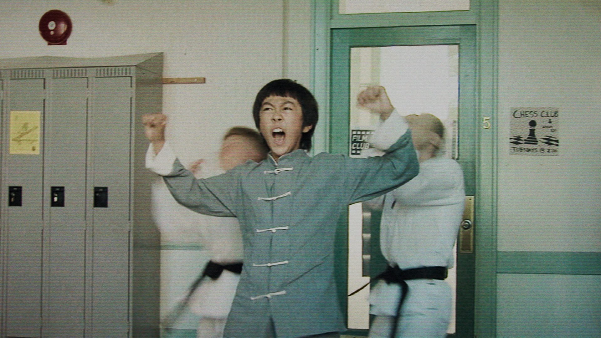 The Bryce Lee Story film image; young boy in a karate outfit lifting his hands triumphantly