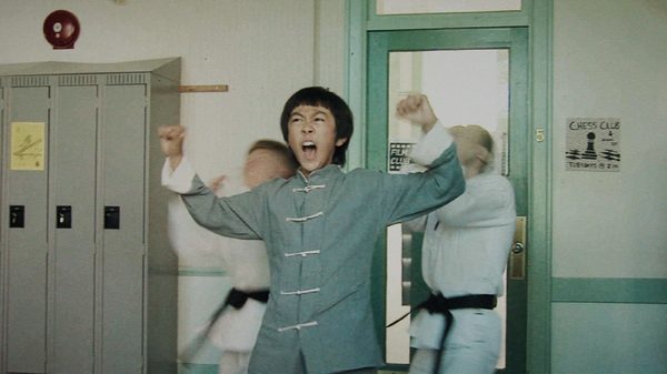 The Bryce Lee Story film image; young boy in a karate outfit lifting his hands triumphantly