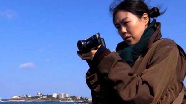 Nowhere to Lay My Eyes film image; woman filming with a camcorder