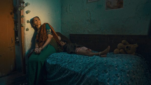 Pankaja film image; woman sitting in a bed with a child lying down next to her