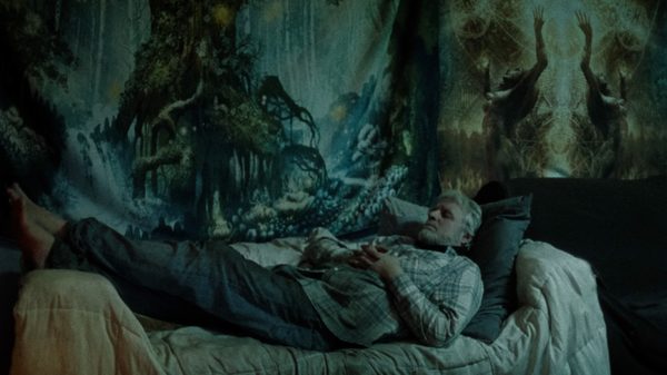 Sweet Captive film image; man lying in a bed next to a painted tree