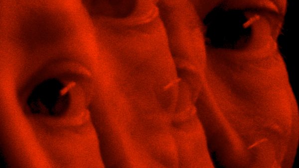 Vulnus film image; overlaid faces under red light