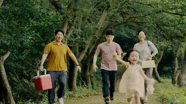The Quiet Applause film image; family walking joyfully down a tree-lined path