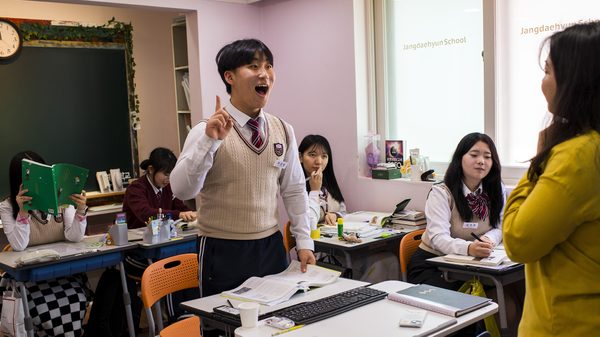 School for Defectors film image; person standing by a desk speaking