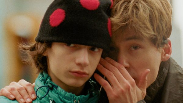 Skinny Bottines film image; man whispering into another man's ear