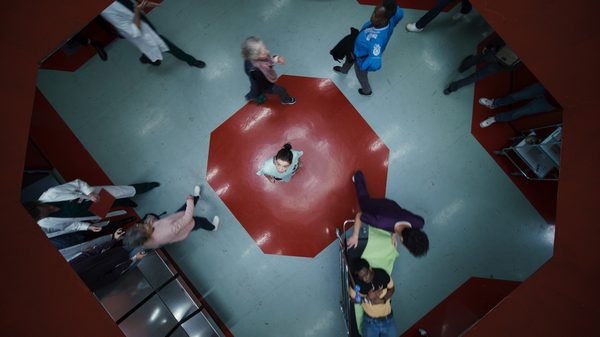 Species film image; top-down perspective on a woman looking up surrounded by people