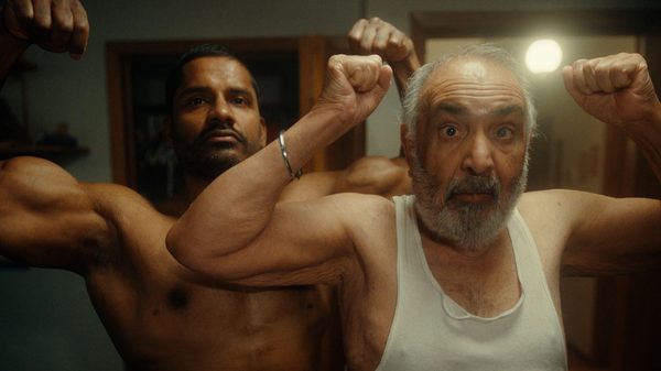 Strong Son film image; two men flexing their arm muscles